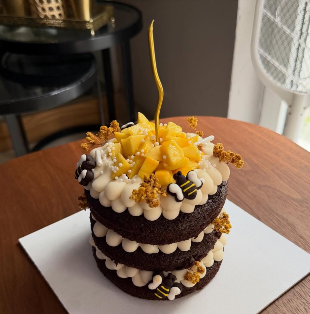 Naked chocolate cake topped with fresh mango and honeycomb