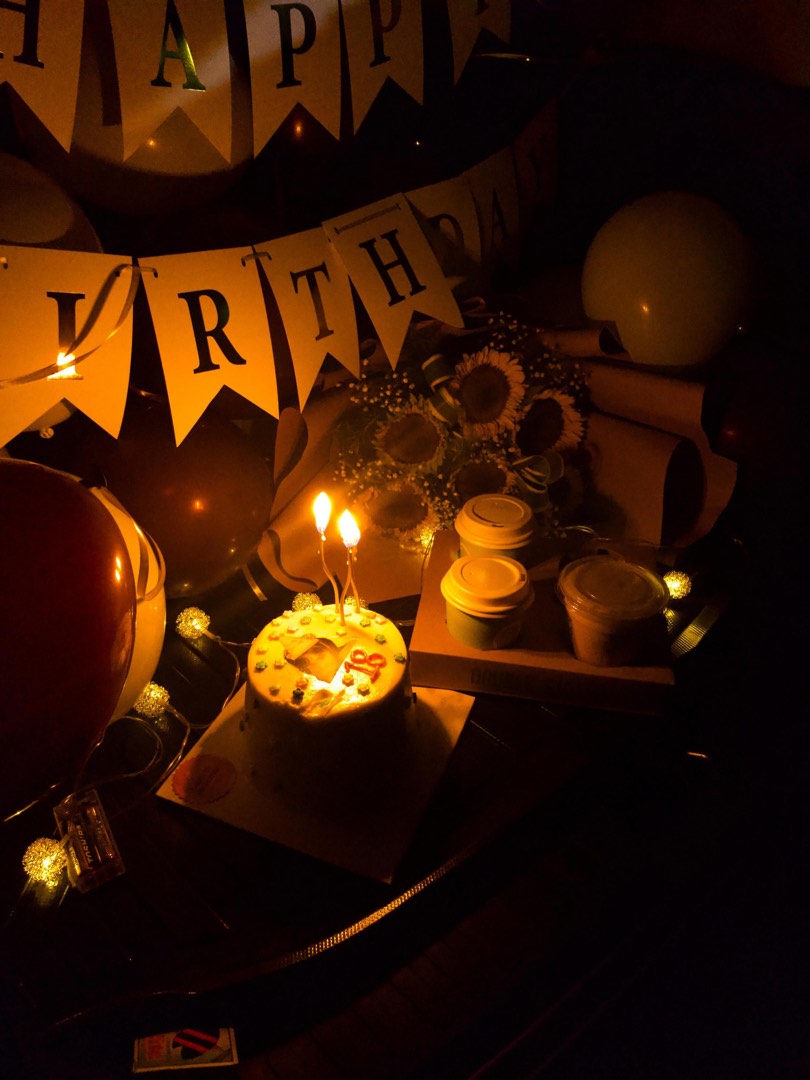A birthday dessert table lit with candles and fairy lights
