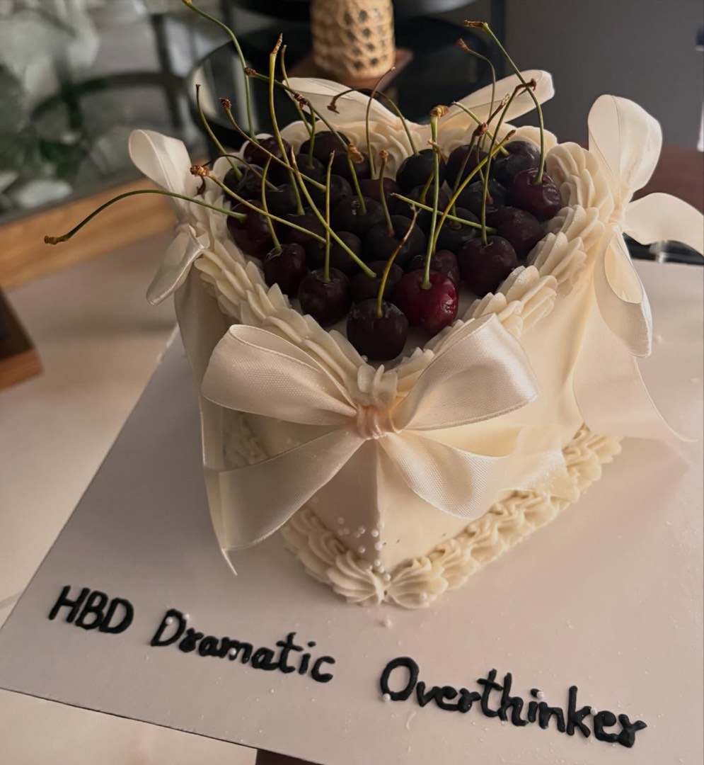 Heart-shaped cake topped with fresh cherries and a ribbon